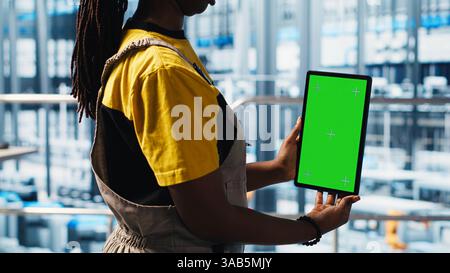 Robotics technician using chroma key device in smart factory calibrating IoT sensors, close up. Engineer using isolated screen tablet in industry 4.0 industrial plant to install machinery Stock Photo
