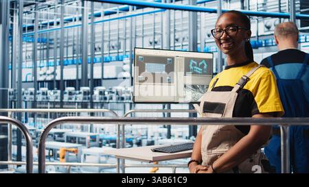 Portrait of cheerful photovoltaics smart factory engineer typing on PC, researching PV materials. Jolly woman in industry 4.0 solar panels plant develops green energy systems prototypes, camera A Stock Photo