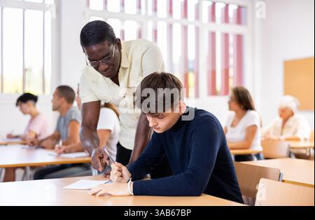 African American teacher helping student solve task during lesson Stock Photo