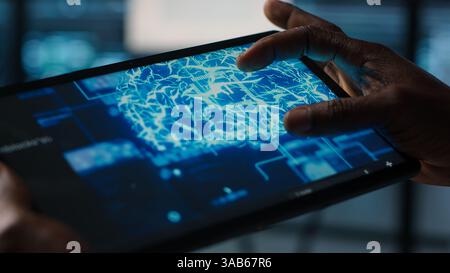 Close up of computer scientist in data center uses AI on tablet, verifying compliance of racks. IT expert using artificial intelligence on device to optimize resource utilization, camera A Stock Photo