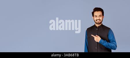 Handsome young Indian man smiling and pointing aside over lilac background Stock Photo