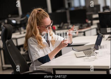 Caucasian woman in a medical gown doing laboratory experiments.  Stock Photo