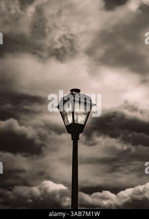 Metal light post with stormy clouds in black and white Stock Photo