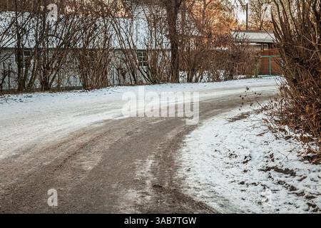 Rural road in Austria covered in ice and snow, emphasizing challenging winter driving conditions and hazards on countryside roads. Stock Photo