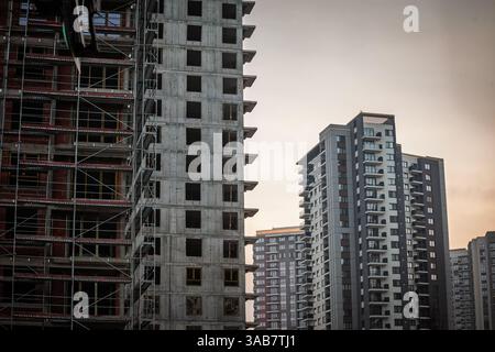 Construction site showing high-rise residential buildings with concrete structures, scaffolding, and modern apartments representing urban real estate Stock Photo