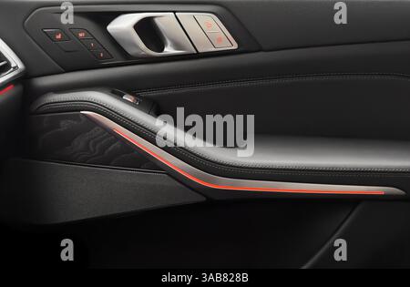 Door handle with power window control buttons. Black perforated leather interior with stitching. Modern car black leather interior details. Stock Photo