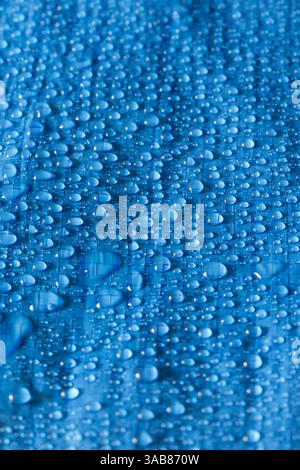 Water rain droplets on blue industrial waterproof tarpaulin sheet background backdrop. Industrial commercial heavy duty material Stock Photo