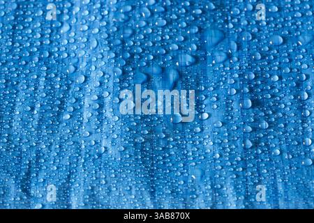 Water rain droplets on blue industrial waterproof tarpaulin sheet background backdrop. Industrial commercial heavy duty material Stock Photo