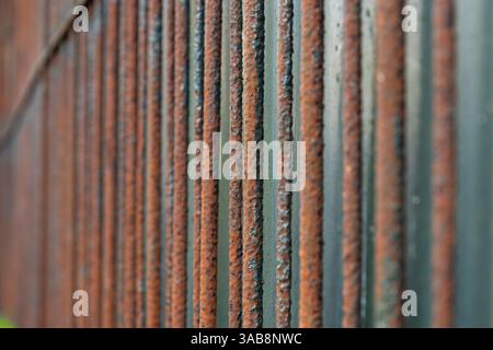 Rusty metal garden fence made of rods, close-up, abstract background . Stock Photo