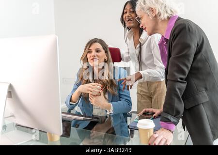 Diverse group of female professionals discussing ideas at office desk, representing collaboration, inclusivity, creativity, teamwork, leadership, and Stock Photo