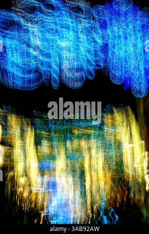 Soft, swirling colors form an abstract landscape of blue and gold lights against a dark background, capturing the dynamic energy of a lively urban set Stock Photo
