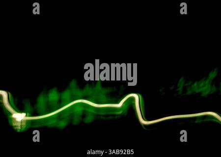 Vivid green light trails weave through a dark space, creating an abstract visual journey. The dynamic movement adds a sense of energy and fluidity to Stock Photo