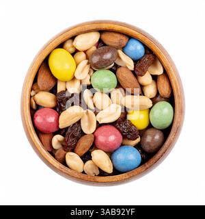 Rainbow trail mix in a wooden bowl. Snack mix of candy coated milk chocolate peanuts, roasted peanuts, raisins, and roasted almonds. Stock Photo