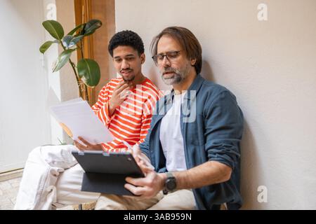 Two colleagues collaborate in a cozy office setting, reviewing documents and discussing plans. A productive work session unfolds, fostering creativity Stock Photo