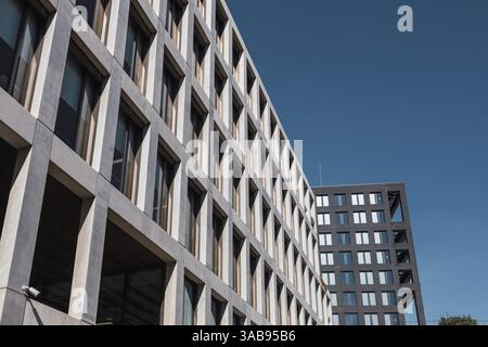 A perspective view of modern urban office buildings with geometric designs against a clear blue sky. Architectural details highlight symmetry and cont Stock Photo