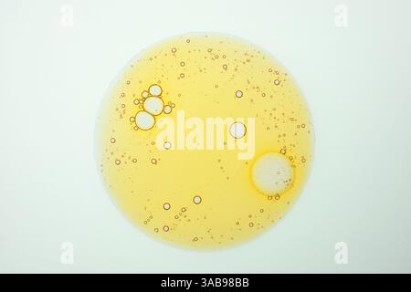 A captivating close up of golden oil droplets for cosmetic, forming an intricate bubble pattern against a clean, white background. Ideal for textures Stock Photo