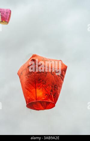 Low angle view of a floating red Chinese lantern released into the sky in Taiwan, inscribed with traditional wishes and blessings for health, happines Stock Photo