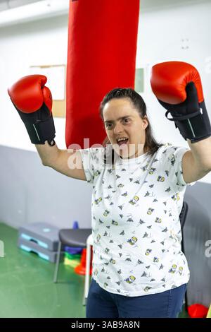 A woman with red boxing gloves enthusiastically practices boxing in a mental health residence, symbolizing empowerment and personal strength in a supp Stock Photo