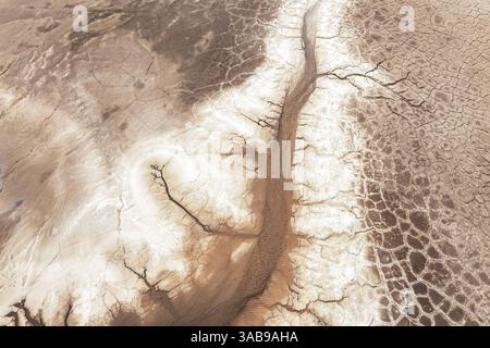 Aerial view of a barren, cracked landscape showcasing intricate patterns of dried earth. The arid terrain emphasizes the effects of a dry climate on t Stock Photo