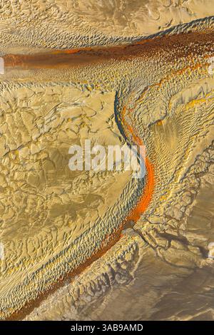 Aerial shot showing a textured, sandy desert terrain with orange streaks creating a river like pattern across the surface, capturing natural abstract Stock Photo