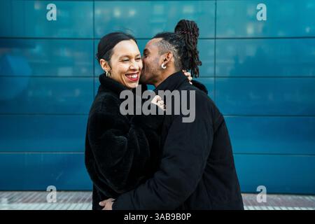 A happy multicultural couple enjoys a tender moment outdoors, embracing love and diversity. The duo's attire blends modern style with traditional allu Stock Photo