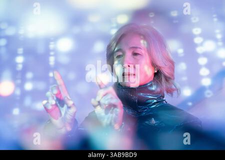 An elderly Asian woman explores the metaverse, engaging with virtual holographic displays. The image captures technology blending with daily life for Stock Photo