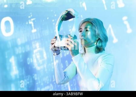 An elderly Asian woman immerses herself in the metaverse using a VR headset. The digital background symbolizes technology and futuristic exploration, Stock Photo
