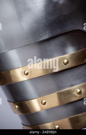 Close-Up Detail of Medieval Shoulder Armor. Textured surface of polished steel spaulders with decorative brass accents. Stock Photo
