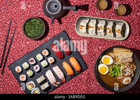 Overhead shot of a Japanese food table with sushi, ramen, dumplings, and tea, captured with strong directional lighting for a vibrant and appetizing l Stock Photo