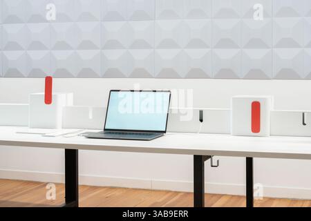 A modern office workspace featuring a laptop on a sleek desk with minimalistic design elements. The backdrop includes geometric wall patterns and styl Stock Photo