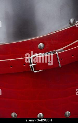 Close-up of a red leather helmet strap with buckle. A detailed close-up shows a vibrant red leather strap with a shiny silver metal buckle, attached t Stock Photo