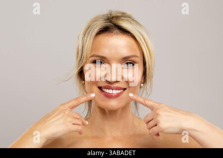 Oral Care. Beautiful Middle Aged Woman Pointing At Her White Teeth Stock Photo