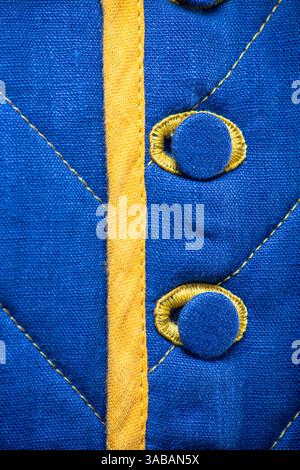 Detailed View of Blue Quilted Textile with Yellow Accents. This close-up showcases the texture of blue quilted fabric featuring a vertical yellow stri Stock Photo