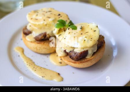 A pair of eggs benedict topped with creamy hollandaise sauce served at a local cafe in Batangas, Philippines Stock Photo