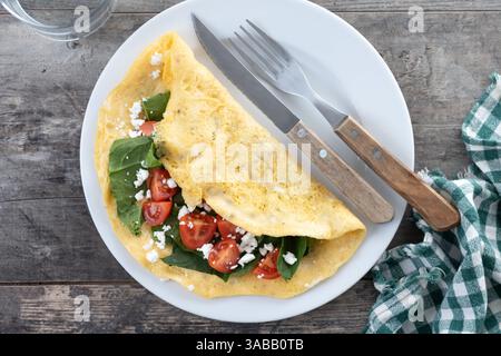 Stuffed omelette with tomatoes and spinach on wooden table Stock Photo