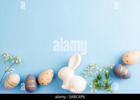 Easter eggs, flowers and ceramic bunny on blue background. Easter concept. Top view, flat lay, copy space. Stock Photo