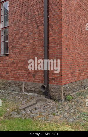 Round metal downspout on a red brick wall. Stock Photo
