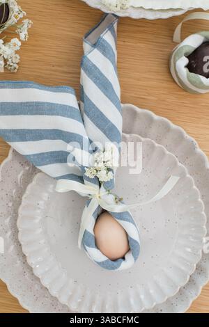 Easter egg wrapped in linen napkin in the shape of bunny with ears. Happy Easter  Stock Photo