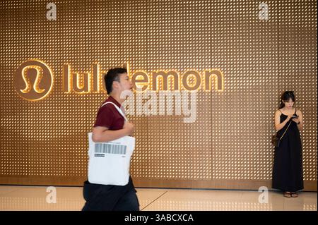 Shoppers walk past the Canadian sportswear clothing band, Lululemon