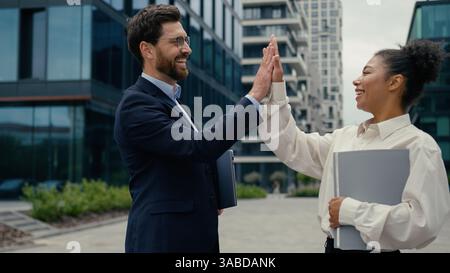 Two multiracial business colleagues friends coworkers meeting greeting high five gesture friendship talking African American woman female Stock Photo