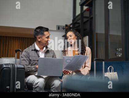 Two Travelers Collaborating on a Project in a Modern Hotel Lobby Stock Photo