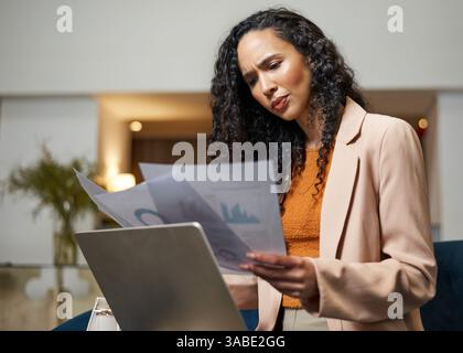 Focused Businesswoman Analyzing Documents During a Business Trip in a Modern Hotel Lobby Stock Photo