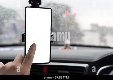 Modern smartphone device gadget mounted on phone holder at car dashboard. Mock-up white screen isolated template. Copyspace for text . Vehicle interio Stock Photo