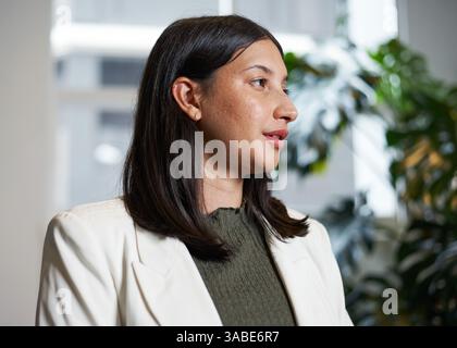 Professional Woman in Formal Attire Posing Indoors Near Natural Light and Green Background Stock Photo