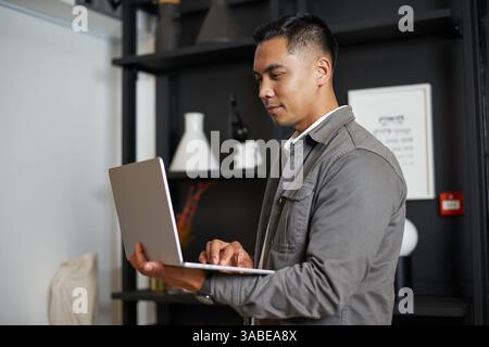 Professional Individual Using a Laptop in a Modern Office Environment with Contemporary Decor Stock Photo