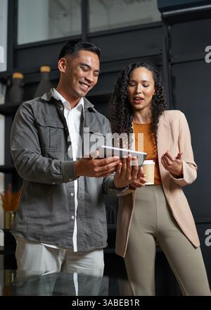 Two Professionals Collaborating in a Modern Office Environment While Reviewing a Digital Tablet Stock Photo