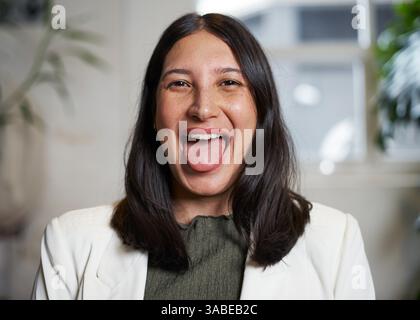 Woman Smiling Playfully Showing Tongue in a Bright and Cheerful Indoor Setting Stock Photo