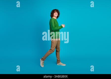 Young man smiling confidently in trendy casual outfit walking against a blue background Stock Photo