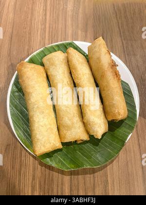 Fried spring rolls on white plate and banana leaves, top view Stock Photo