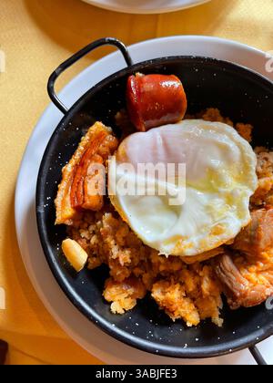 Crumbs with chorizo, bacon and fried egg. Spain. Stock Photo